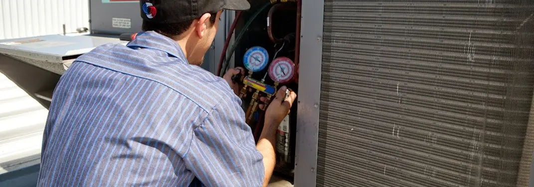 HVAC technician servicing a condenser unit in Marblehead
